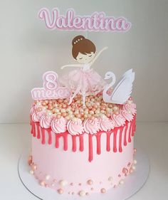 a birthday cake decorated with pink icing and white frosting, featuring a ballerina on top