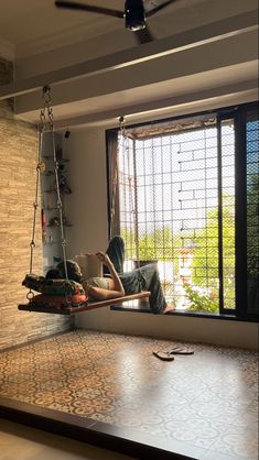 a man laying on a swing in front of a window