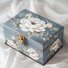 a blue box with white flowers painted on the side and gold hardware at the top