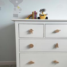 a white dresser with gold knobs in a child's room