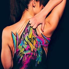 the back of a woman's body with colorful graffiti art on her upper half