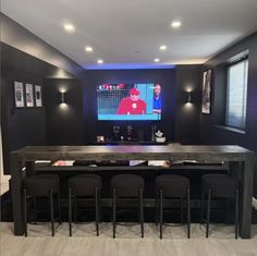 a room with chairs and a table in front of a tv on the wall behind it