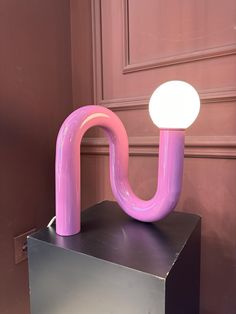 a pink lamp sitting on top of a metal box