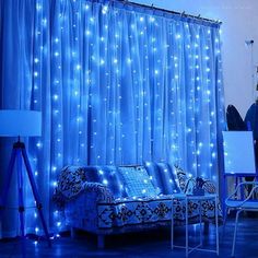 a living room with blue lights on the curtains and couches in front of it