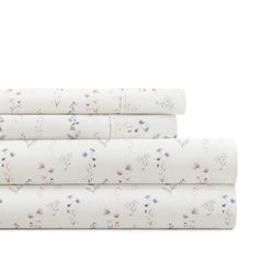 three sheets with floral designs on them, one in white and the other in pink