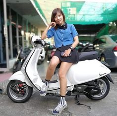 a woman sitting on top of a white scooter