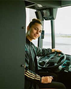 a man sitting in the driver's seat of a bus with his hands on the steering wheel