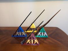 three harry potter houses made out of wood and metal with wands in them on a wooden table