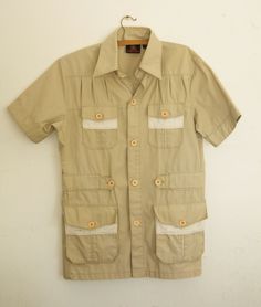 Up for sale is a pre-owned Vintage 1970’s Mens Photographer & Travel Safari Khaki Button Down Short Sleeve Shirt by EL TORO BRAVO. This Shirt is 65% polyester and 35% cotton, made in Hong-Kong, and comes with labels. It has 4 pockets on front.   Size: 40 Width: 53 cm / 20.86” Armpit to Armpit Length: 75 cm / 29.52” Top to Bottom   Condition: Previously Worn, Minor Wear, in Good to Very Good condition, BUT there are few stains that surly can be removed (please see pics).     PLEASE SEE PICTURES T Travel Safari, Bad People, Photographer Travel, Ugly Duckling, Button Down Short Sleeve, Safari Style, Mens Khakis, Mens Shirt, Fishing Trip