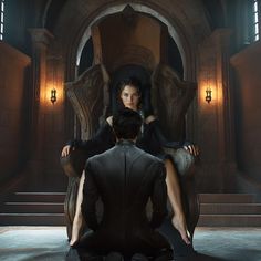 a woman sitting on top of a chair next to a man in a black suit