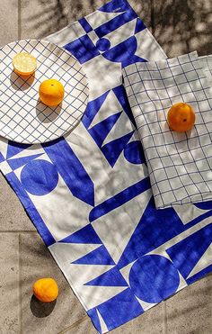 oranges are sitting on top of a blue and white tablecloth with geometric designs