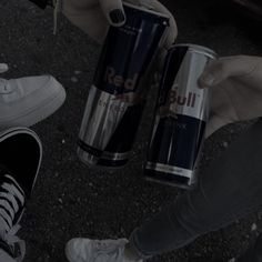 two people holding cans of red bull energy drink in their hands, while one person holds the other's hand