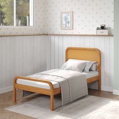 a small bed sitting in a bedroom next to a wall with white and gray polka dots on it