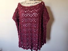 a red crocheted sweater hanging on a white wall