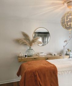 a bed room with a neatly made bed and a round mirror on the wall above it