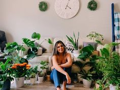 a woman is sitting on the floor in front of some houseplants and plants