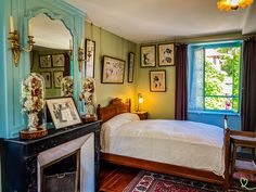 a bedroom with green walls and pictures on the wall above the bed, along with a fireplace