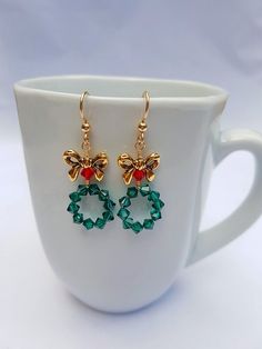 These adorable Christmas Wreath Earrings are Handmade with Emerald Green and Red Swarovski Crystal Bicone Beads and Tierra Cast, Lead-Free Pewter Bow Beads. 14K Gold Filled Ear Wire by Tierra Cast has been used. Meticulously wire wrapped with Tarnish Resistant 14k Gold Plated Wire.  Charming yet Holiday Dangle Earrings With Ear Wire, Holiday Jewelry With Matching Earrings, Handmade Jewelry For Christmas Celebration, Christmas Jewelry Gift With Matching Earrings, Christmas Jewelry Gift Set With Matching Earrings, Christmas Jewelry Set As Gift With Matching Earrings, Dangle Jewelry For Christmas Celebration, Christmas Dangle Jewelry For Celebration, Christmas Celebration Dangle Jewelry