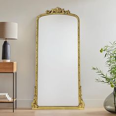 a large mirror sitting on top of a wooden floor next to a vase filled with flowers