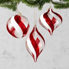 three red and white ornaments hanging from a christmas tree