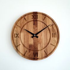 a wooden clock with roman numerals is shown on a white wall in this image