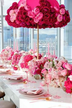 the table is set with pink and white flowers on it, along with candles and place settings