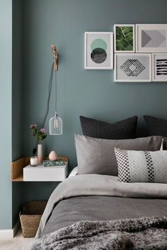 a bedroom with green walls and pictures on the wall above the bed, along with pillows