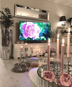 a living room with candles, flowers and a flat screen tv on the wall in front of it