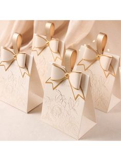 four small white gift bags with bows on them