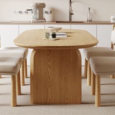 a wooden table with four chairs around it in a white room next to a counter