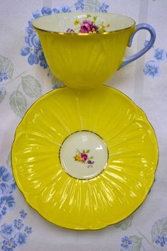 two yellow dishes sitting on top of a floral tablecloth covered table next to each other