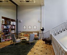 a living room filled with furniture next to a stair case and bookshelf on the wall