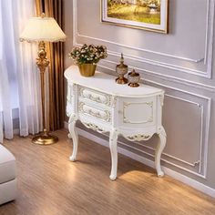 a white table with flowers on it in front of a painting and two lamps next to a couch