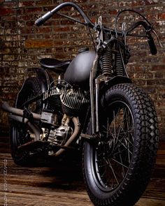 a black motorcycle parked in front of a brick wall