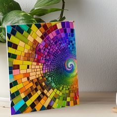 a colorful art piece on top of a table next to a potted green plant