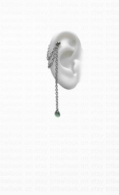 an ear with a chain attached to it and a green bead hanging from the side