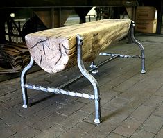 a wooden bench sitting on top of a brick floor next to a metal frame table