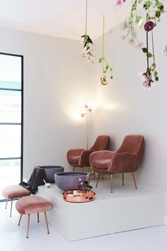 a room with pink chairs and flowers hanging from the ceiling