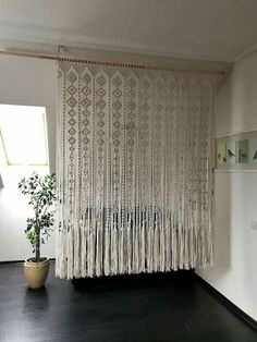 a room with a potted plant on the floor and curtains hanging from the wall