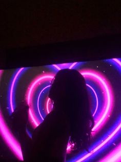 a woman standing in front of a tv with neon lights on it's side