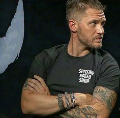 a man with his arms crossed sitting in front of a black background wearing a shirt that says spotter speed shop