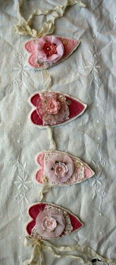 three pink shoes with flowers on them are sitting on a white cloth covered tablecloth