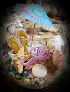 an octopus in a glass bowl filled with rocks, shells and other sea life items