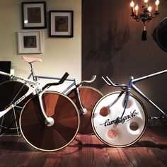 two old fashioned bicycles sitting next to each other in a room with pictures on the wall