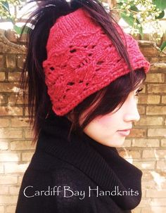 a woman wearing a red knitted headband in front of a brick wall and tree