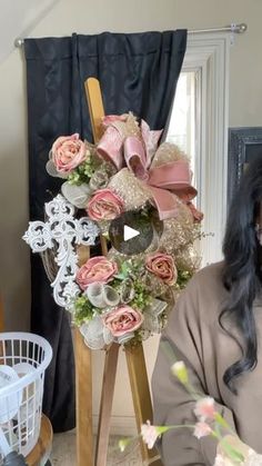 a woman sitting in front of a flower arrangement on top of a wooden easel