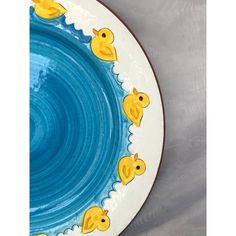 a blue and white plate with yellow rubber ducks on the rim, in front of a gray background