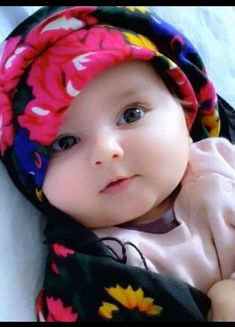 a baby wearing a flowered hat laying on top of a bed