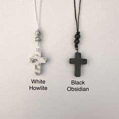 two black and white cross necklaces hanging on a wall