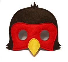 a red and black mask with a yellow bird on it's face, sitting on a white surface